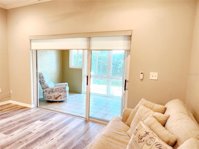 living room featuring wood finished floors, ornamental molding, and baseboards