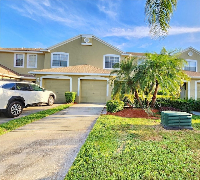 11246 Kapok Grand Cir, Madeira Beach, FL 33708 - view of property with a garage, stucco siding, driveway, and central AC