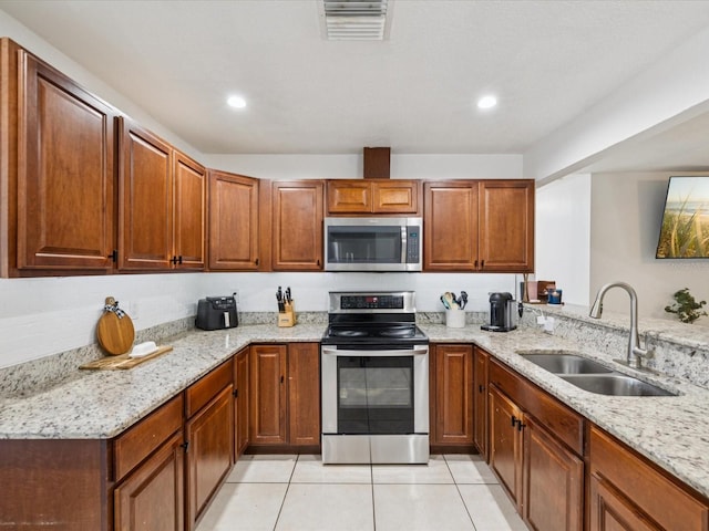 232 Emerald Ln, Largo, FL 33771 - kitchen featuring stainless steel appliances, light stone countertops, light tile patterned floors, recessed lighting, and brown cabinetry