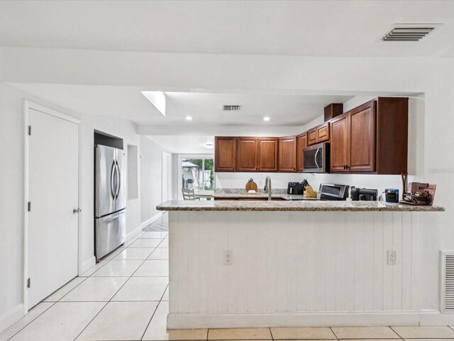 232 Emerald Ln, Largo, FL 33771 - kitchen featuring appliances with stainless steel finishes, a peninsula, light stone counters, light tile patterned floors, and recessed lighting