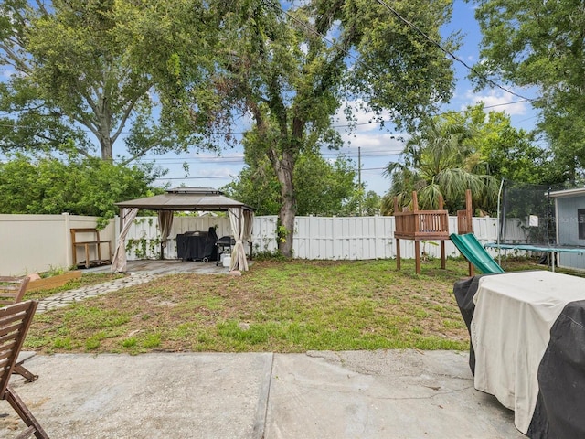 232 Emerald Ln, Largo, FL 33771 - fenced backyard featuring a trampoline, a gazebo, a patio, and a playground