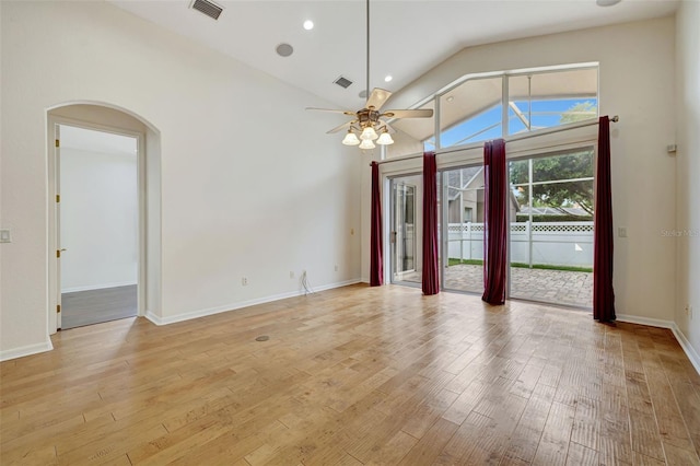 empty room featuring a ceiling fan, visible vents, arched walkways, light wood finished floors, and lofted ceiling