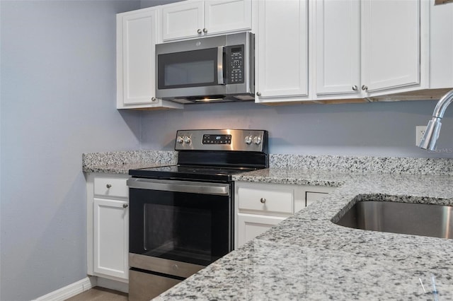 kitchen with a sink, appliances with stainless steel finishes, and white cabinetry