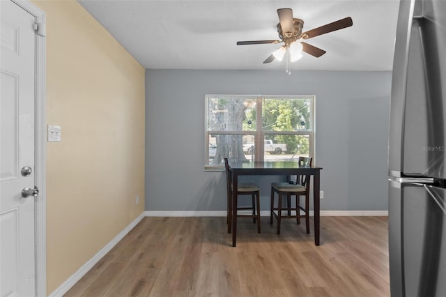 dining room featuring baseboards, light wood finished floors, and a ceiling fan