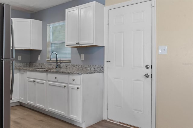 kitchen with light wood finished floors, white cabinetry, and freestanding refrigerator