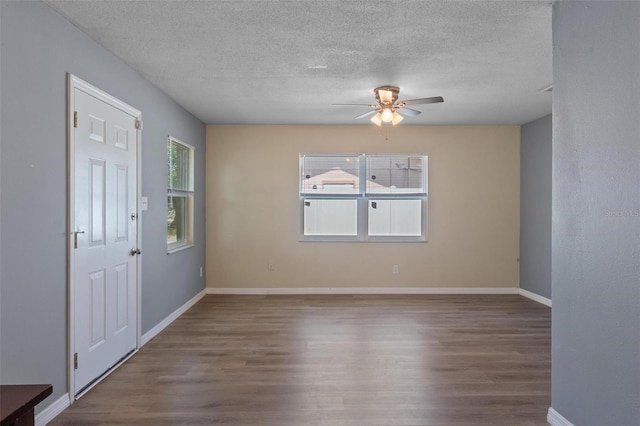 interior space with baseboards, a ceiling fan, wood finished floors, and a textured ceiling
