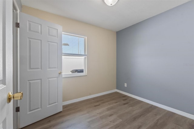 empty room with baseboards and wood finished floors