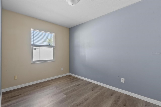 unfurnished room with baseboards and wood finished floors