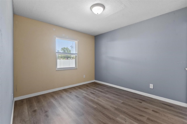 spare room with baseboards, a textured ceiling, and wood finished floors