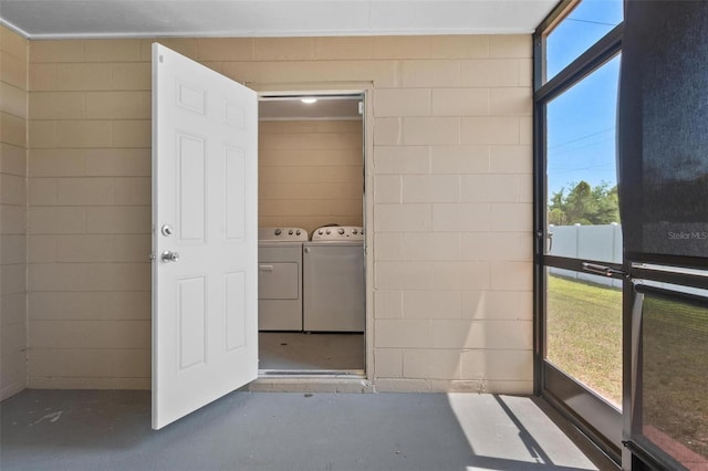 laundry area featuring laundry area, concrete block wall, and washer and clothes dryer