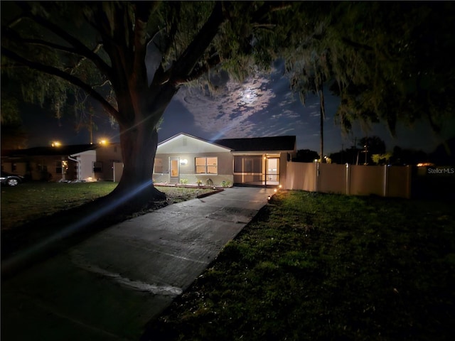 bungalow-style house with a yard, fence, driveway, and stucco siding