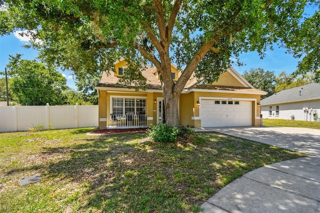 view of front of home with stucco siding, fence, a front lawn, an attached garage, and driveway