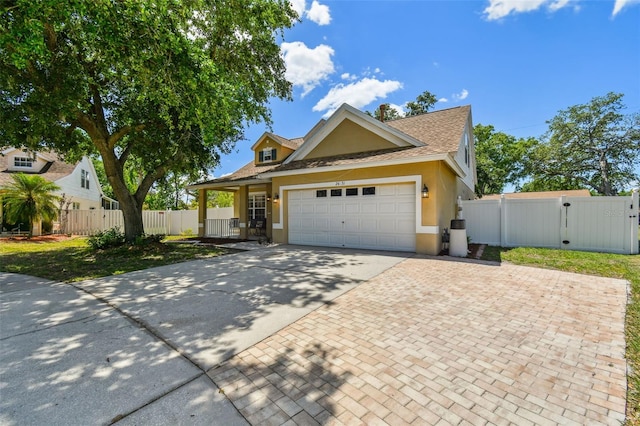 view of front of home with stucco siding, a gate, driveway, an attached garage, and fence