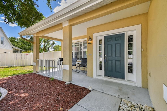 property entrance with stucco siding and fence