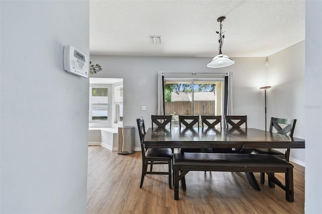 dining space featuring visible vents, baseboards, wood finished floors, and a textured ceiling