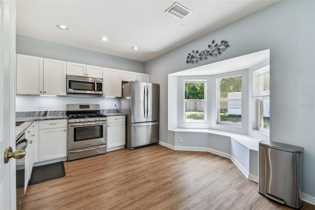 kitchen with light wood-style flooring, white cabinetry, visible vents, stainless steel appliances, and baseboards