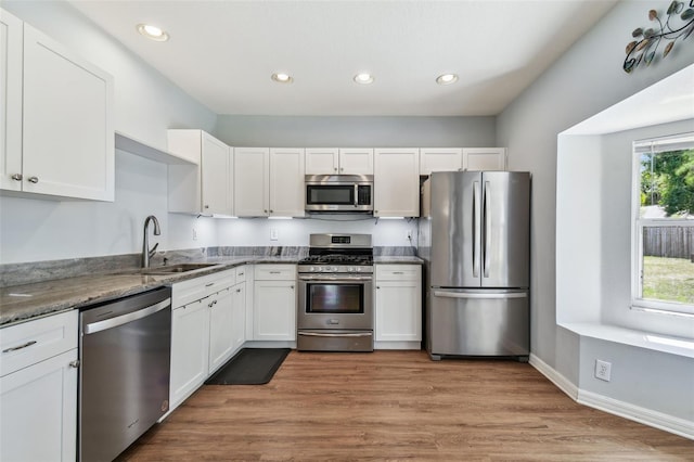 kitchen featuring light stone countertops, white cabinetry, a sink, and appliances with stainless steel finishes