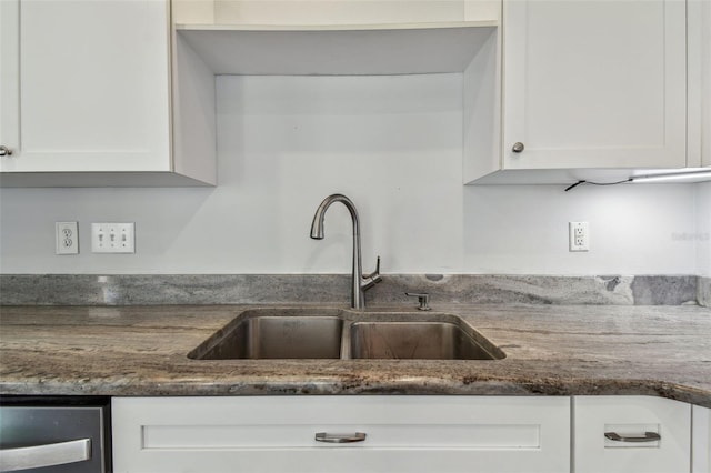 kitchen featuring dark stone counters, a sink, and white cabinetry