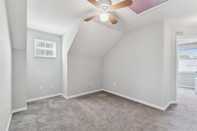 additional living space with a healthy amount of sunlight, carpet flooring, visible vents, and ceiling fan
