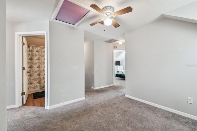 carpeted empty room featuring attic access, ceiling fan, baseboards, and visible vents