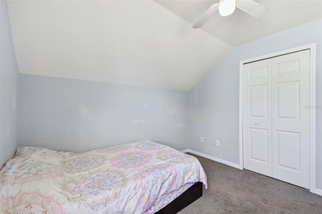 carpeted bedroom with baseboards, a closet, vaulted ceiling, and ceiling fan