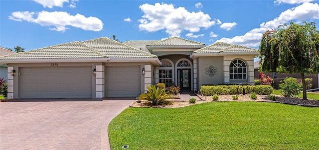 2875 Grazeland Dr, Sarasota, FL 34240 - mediterranean / spanish house with an attached garage, decorative driveway, stucco siding, and a front lawn