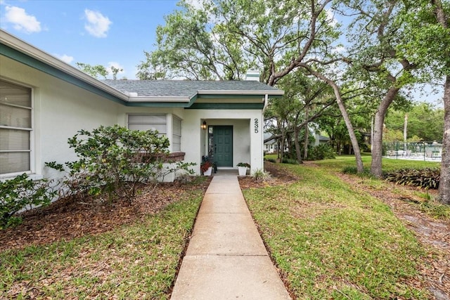 235 Woodridge Cir, Oldsmar, FL 34677 - doorway to property with a lawn and stucco siding
