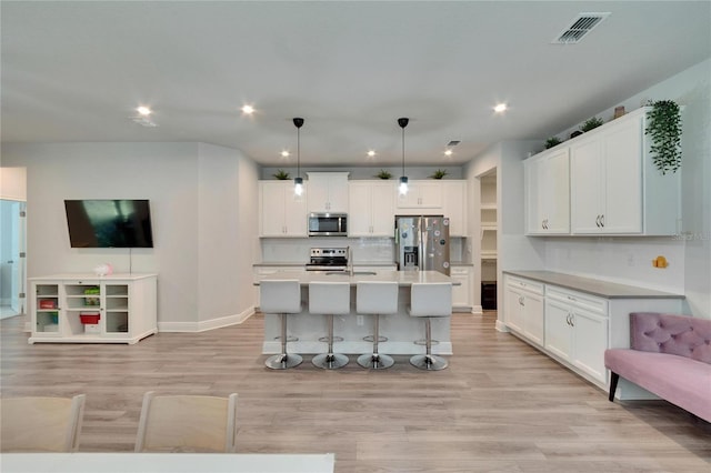 kitchen featuring open floor plan, light wood-style flooring, a kitchen bar, and stainless steel appliances
