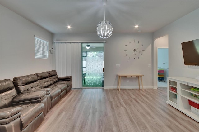 living area with light wood-type flooring, ceiling fan with notable chandelier, baseboards, and recessed lighting