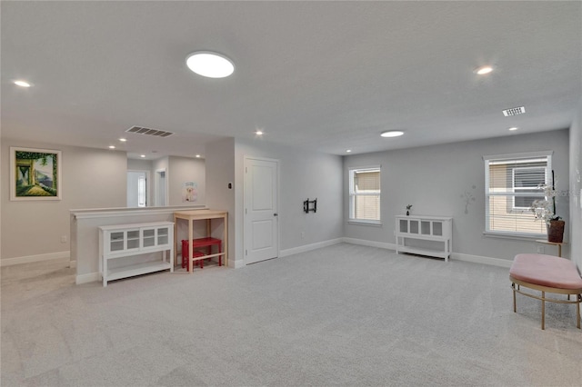 below grade area with visible vents, baseboards, carpet flooring, and a healthy amount of sunlight