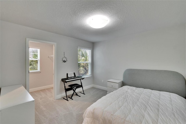 bedroom featuring light carpet, baseboards, and a textured ceiling