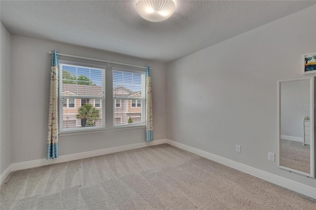 carpeted empty room with baseboards and a textured ceiling