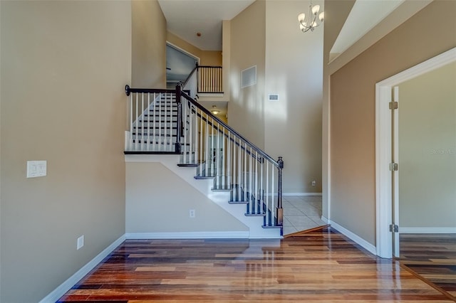 11386 Churchhill Trl, Seminole, FL 33772 - staircase featuring baseboards, a chandelier, a high ceiling, visible vents, and wood finished floors
