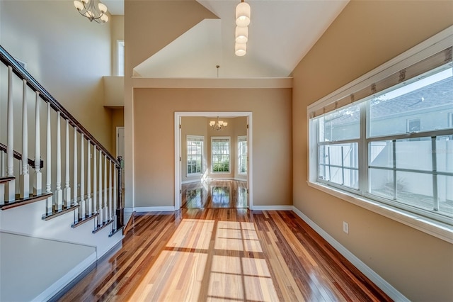 11386 Churchhill Trl, Seminole, FL 33772 - foyer entrance featuring a notable chandelier, baseboards, stairs, high vaulted ceiling, and wood finished floors
