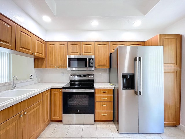 kitchen with recessed lighting, light tile patterned floors, light countertops, appliances with stainless steel finishes, and a sink