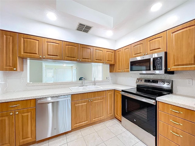 kitchen with tasteful backsplash, visible vents, a sink, appliances with stainless steel finishes, and brown cabinetry