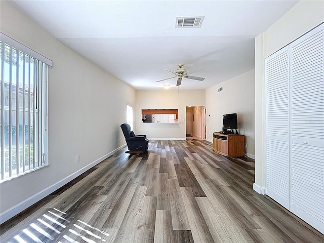 unfurnished living room with baseboards, visible vents, dark wood-style flooring, and a ceiling fan