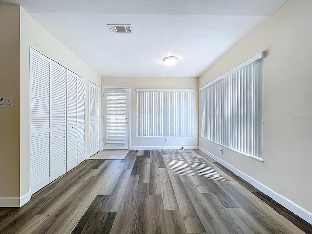 unfurnished bedroom featuring visible vents, baseboards, and dark wood-style floors