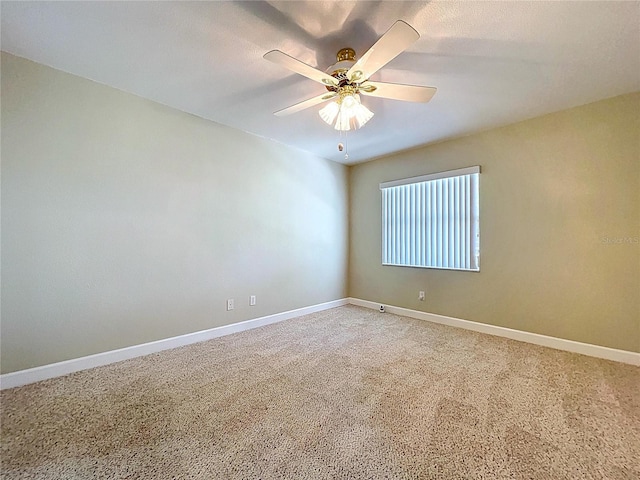 carpeted empty room featuring baseboards and a ceiling fan