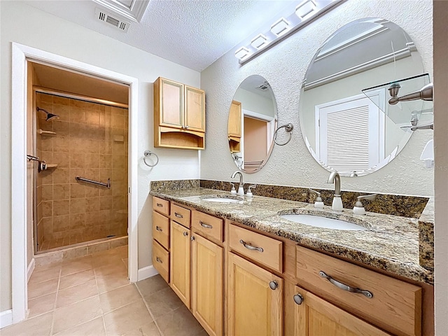 full bath featuring a shower stall, tile patterned flooring, visible vents, and a sink