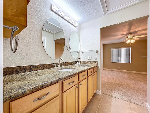 bathroom with ceiling fan, a textured ceiling, double vanity, and a sink