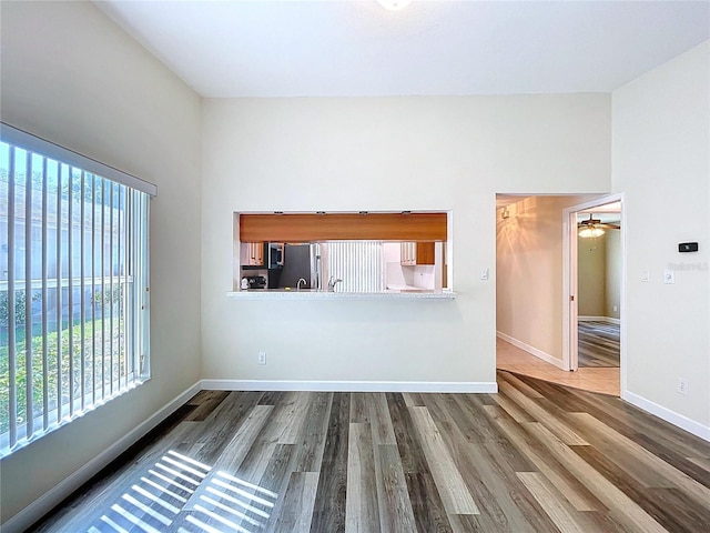 unfurnished living room with wood finished floors, ceiling fan, and baseboards