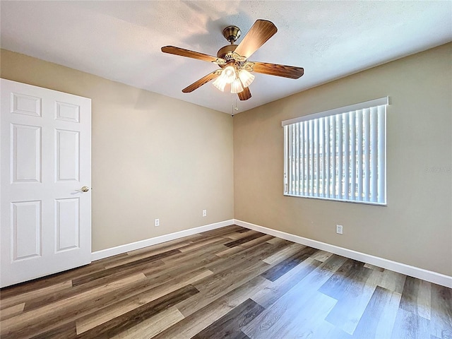 unfurnished room featuring dark wood-style flooring, baseboards, and a ceiling fan
