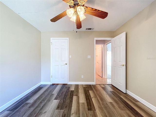 unfurnished bedroom with ceiling fan, baseboards, dark wood finished floors, and visible vents