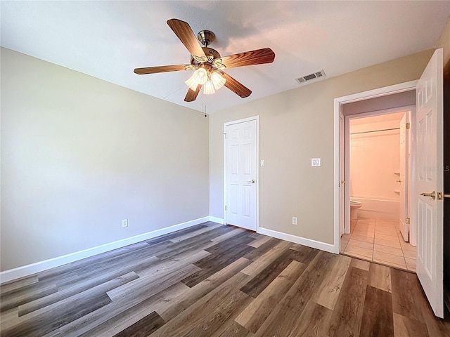 unfurnished bedroom with dark wood-type flooring, ceiling fan, baseboards, and visible vents