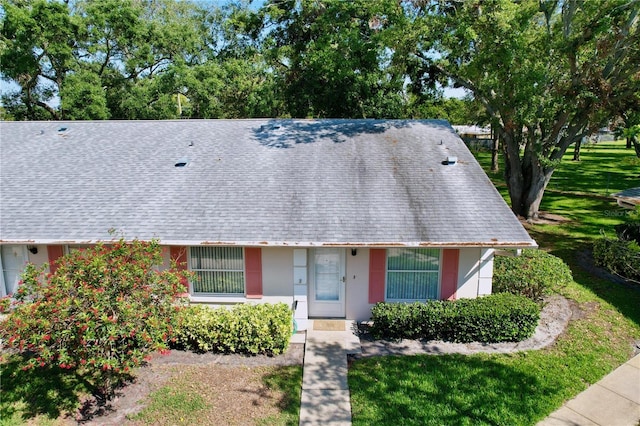 view of front of property featuring a front yard, stucco siding, and a shingled roof