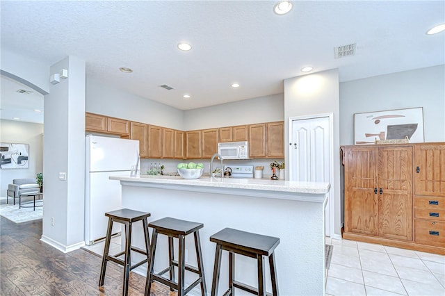 16501 Sandhill Crane Dr, Spring Hill, FL 34610 - kitchen featuring white appliances, arched walkways, light countertops, a kitchen bar, and recessed lighting