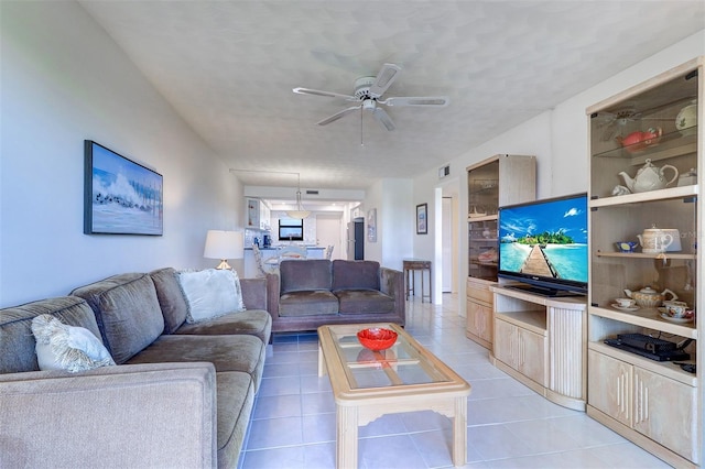 living area with light tile patterned flooring, ceiling fan, and a textured ceiling