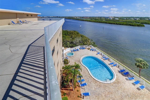 pool featuring fence, a water view, and a patio area