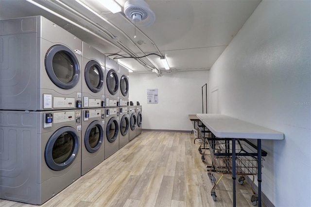 community laundry room with stacked washing maching and dryer, wood finished floors, and baseboards